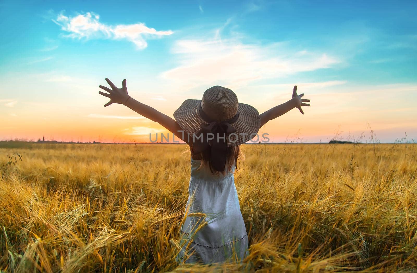 A child looks at the sunset in a wheat field. Selective focus. Kid.