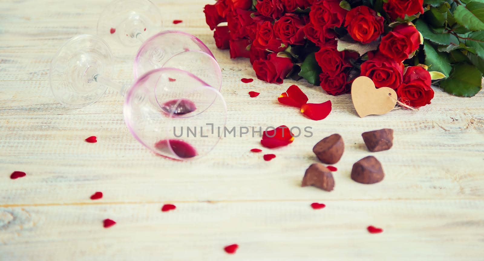 A bouquet of red roses and red wine in glasses. Valentine's Day. Selective focus. Holiday.