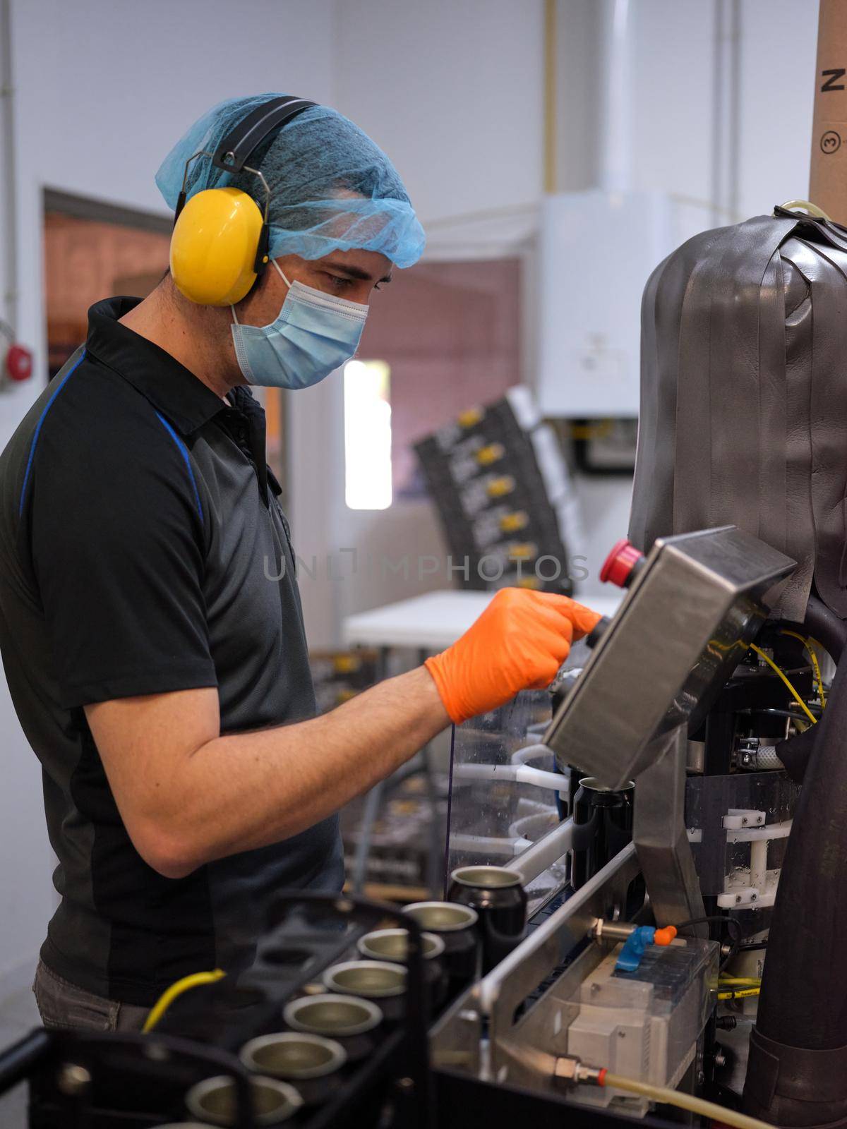 Vertical photo of a man working with an electronic beer packaging machine in a brewery