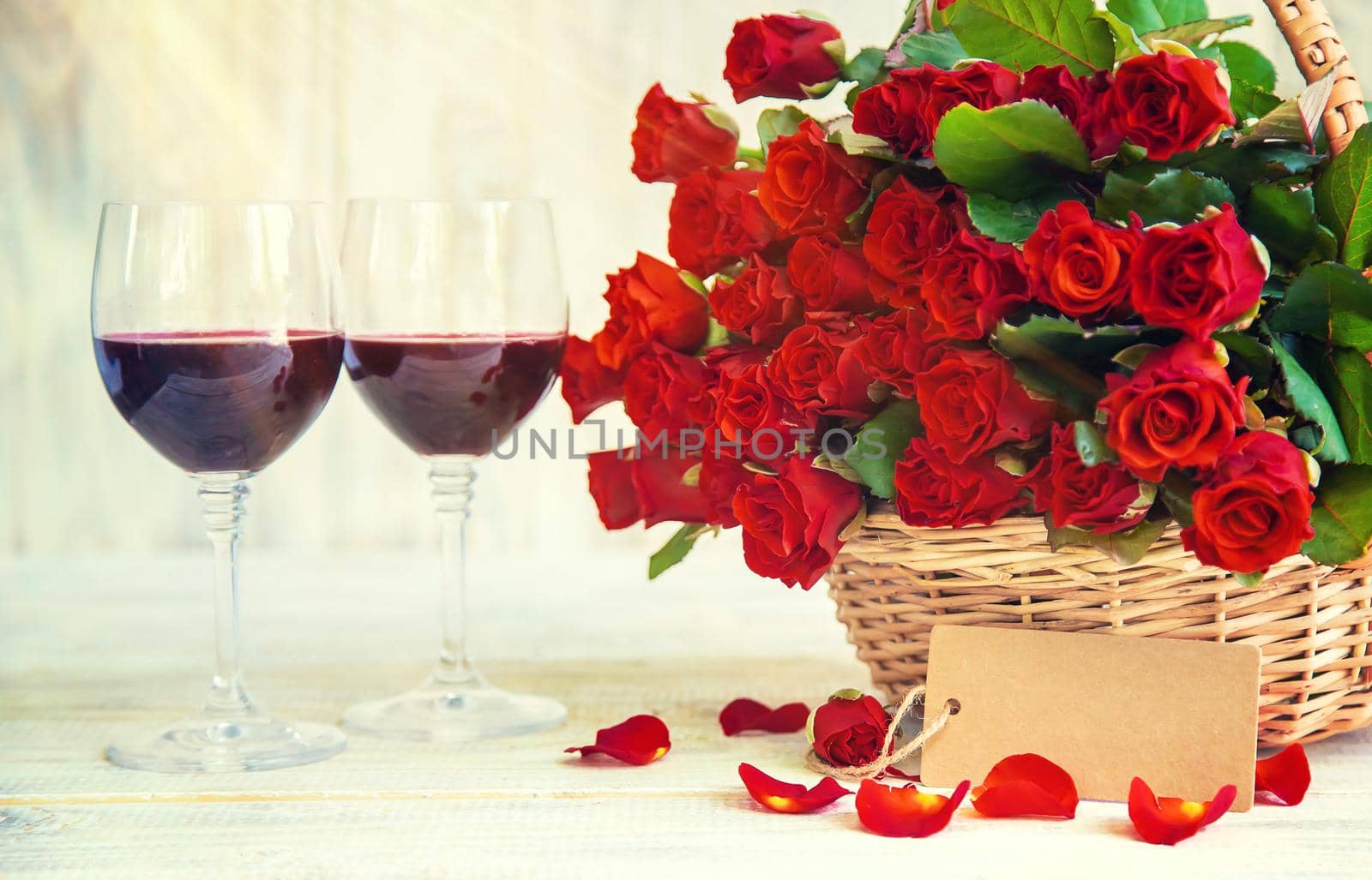 A bouquet of red roses and red wine in glasses. Valentine's Day. Selective focus. Holiday.
