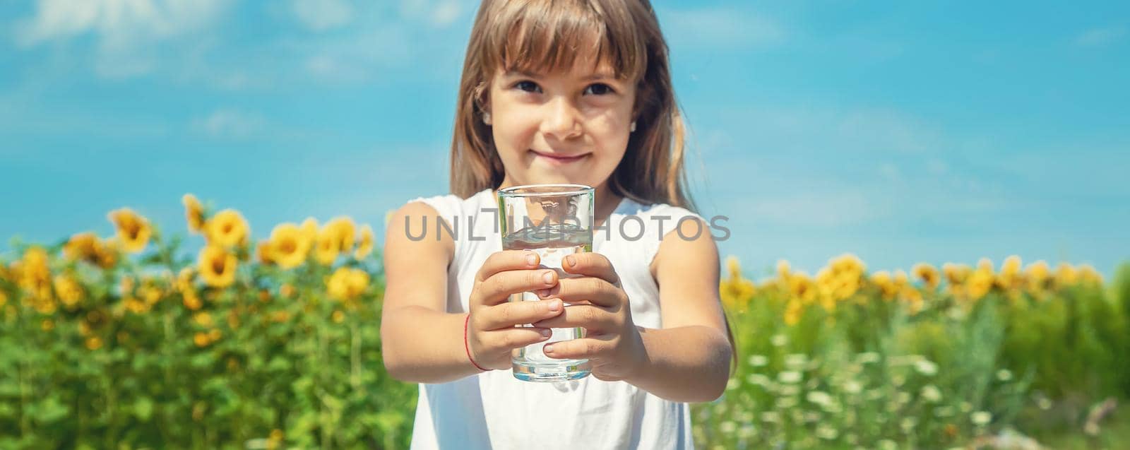 A child drinks water on the background of the field. Selective focus. by yanadjana