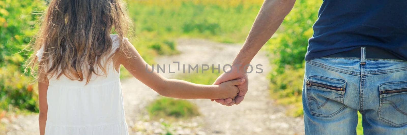 Father and daughter walk holding hands. Selective focus. nature.