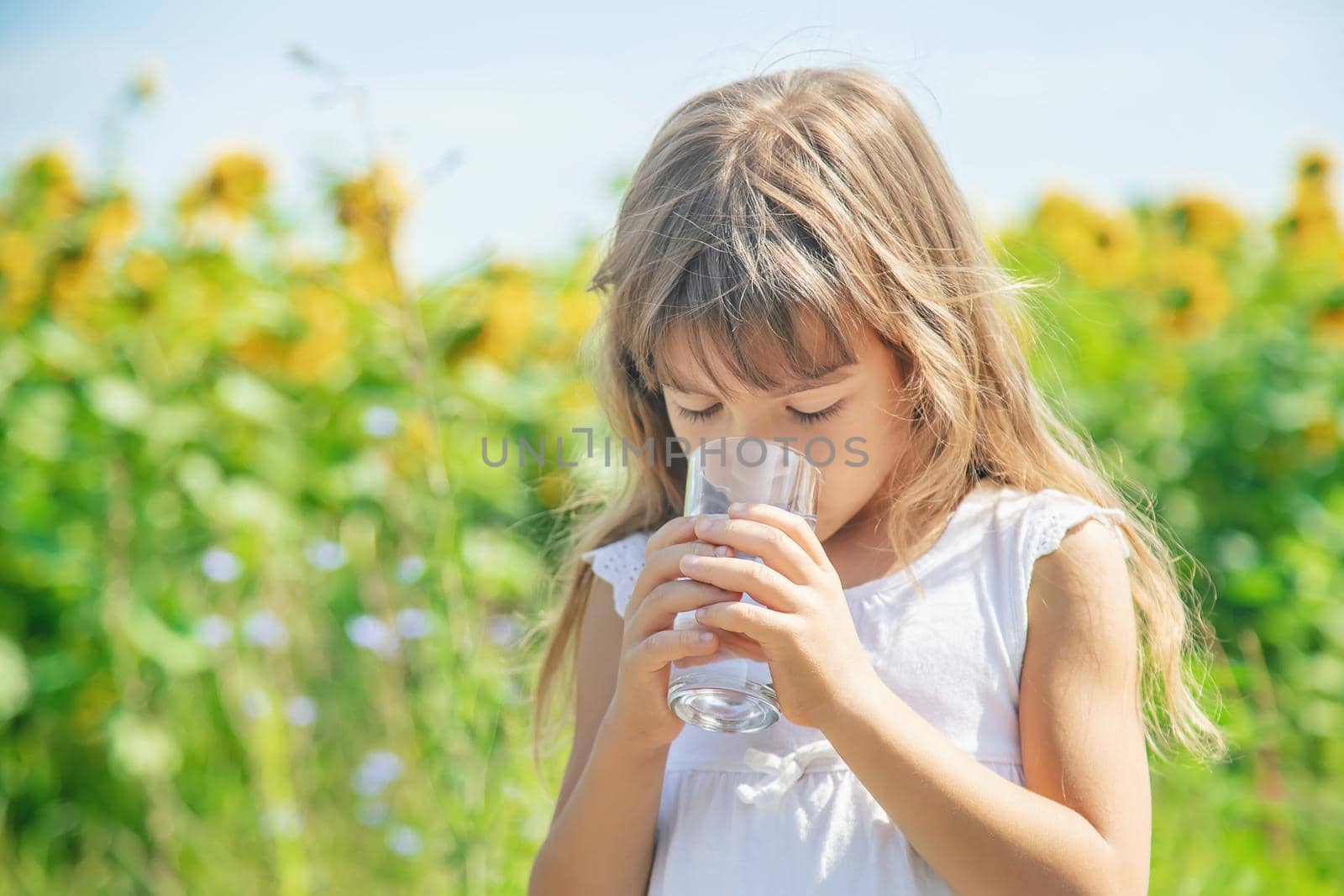 A child drinks water on the background of the field. Selective focus. by yanadjana