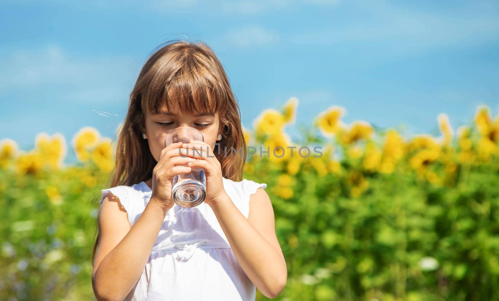 The child drinks water from a glass. Selective focus. Food.