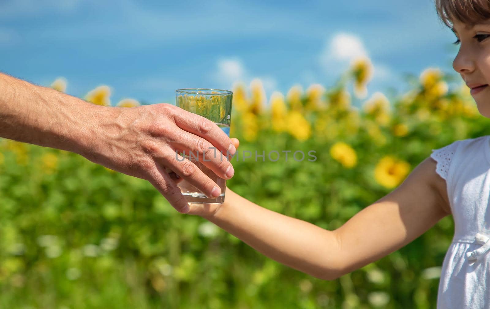 The child and father are holding a glass of water in their hands. Selective focus. Kid.