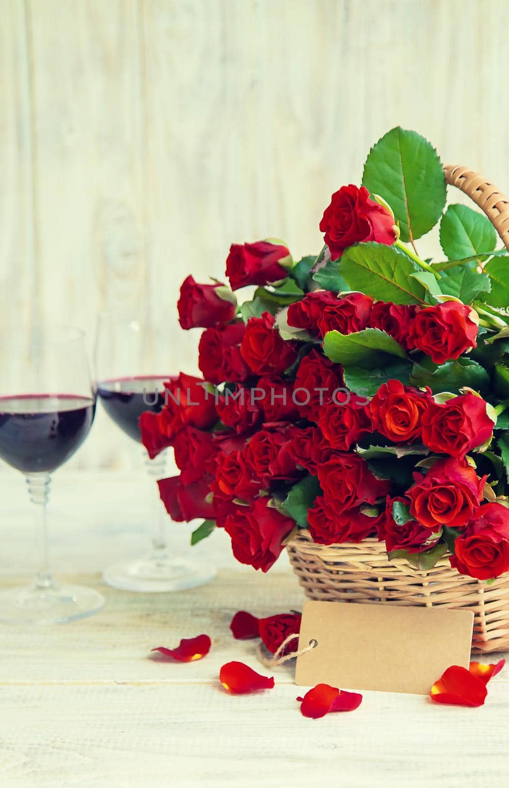 A bouquet of red roses and red wine in glasses. Valentine's Day. Selective focus. Holiday.
