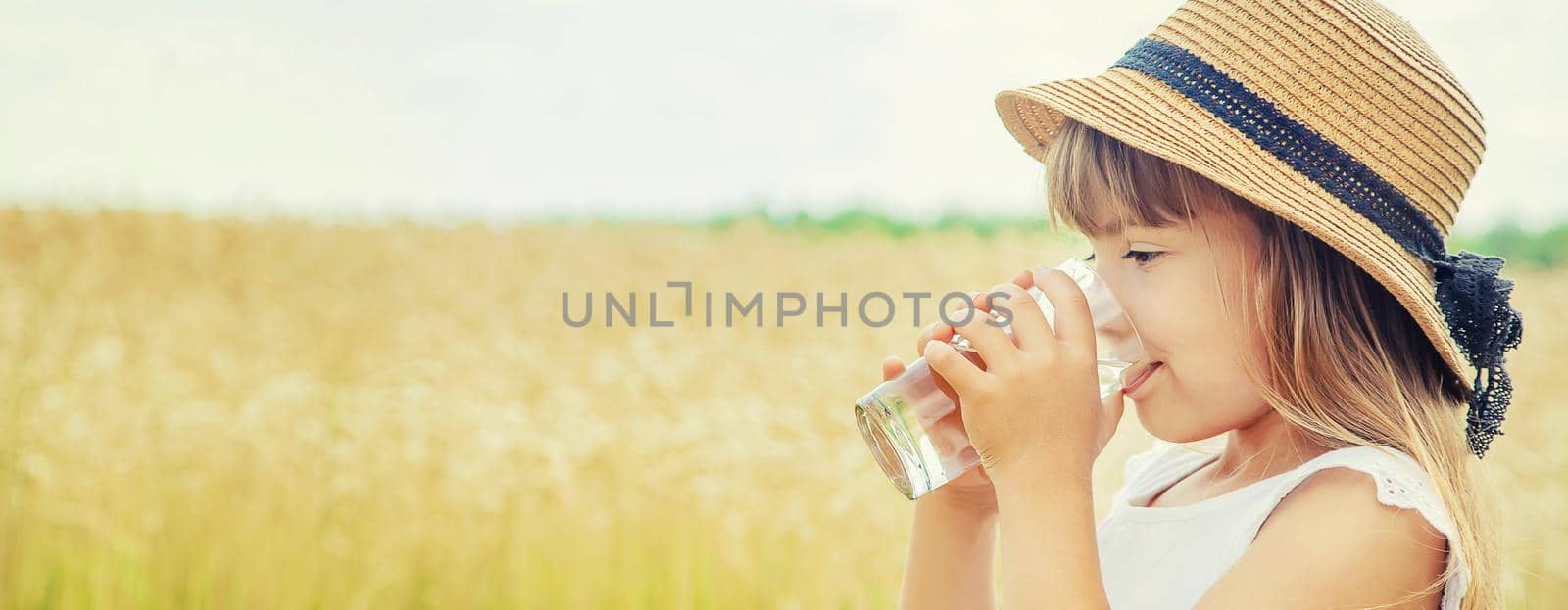 A child drinks water on the background of the field. Selective focus. by yanadjana