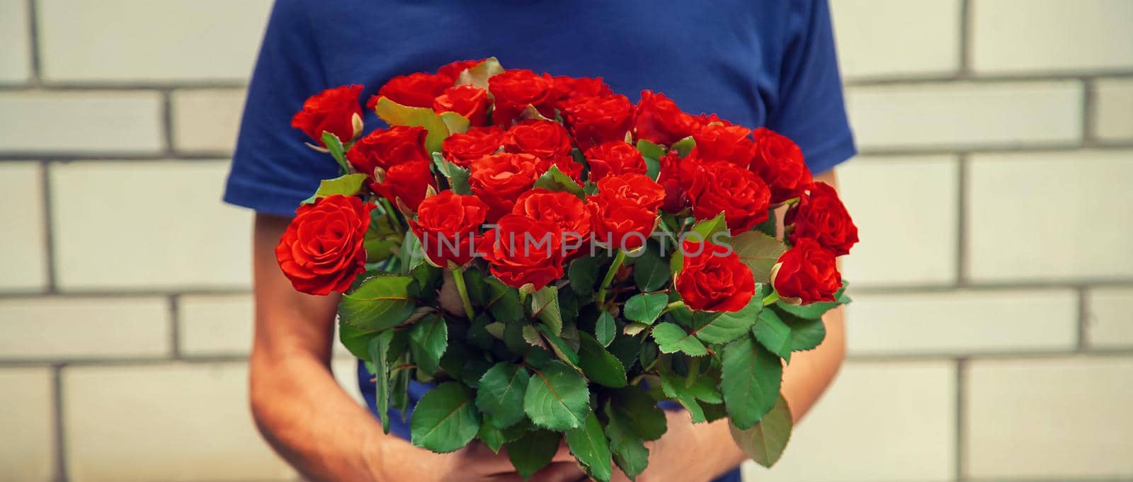 A bouquet of red roses in the hands of a man. Selective focus. Holiday.