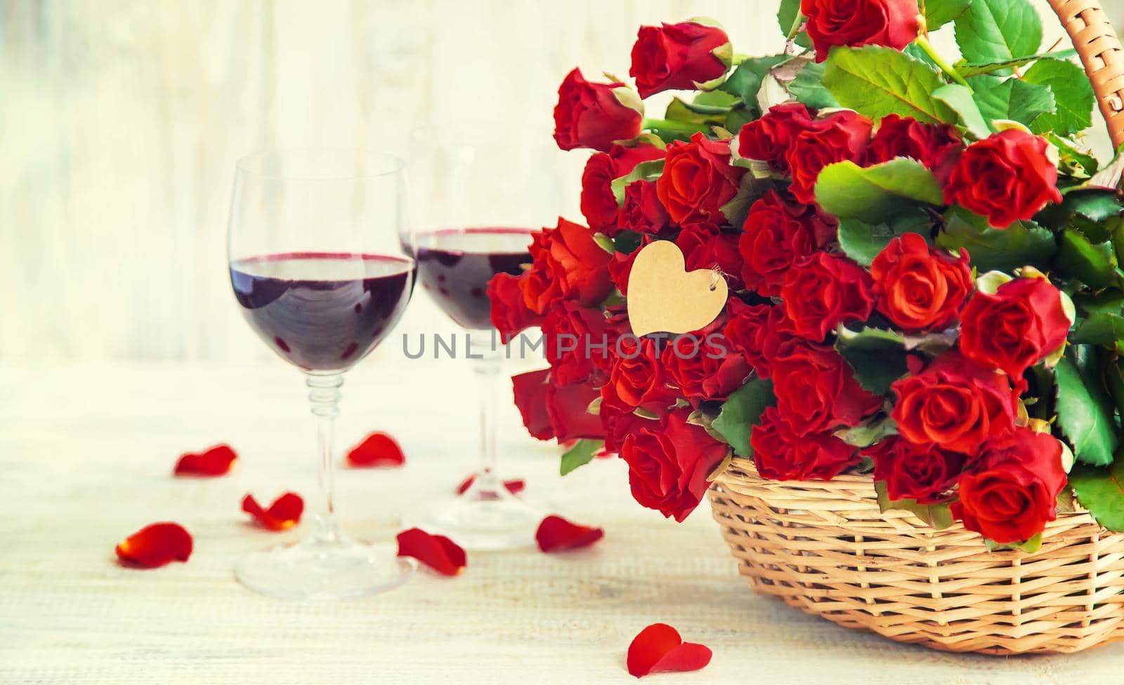 A bouquet of red roses and red wine in glasses. Valentine's Day. Selective focus. Holiday.