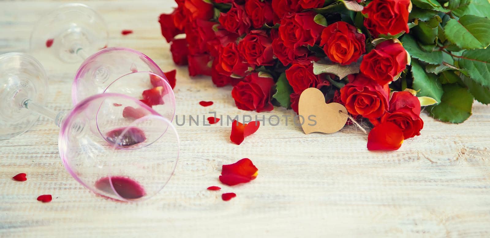 A bouquet of red roses and red wine in glasses. Valentine's Day. Selective focus. by yanadjana