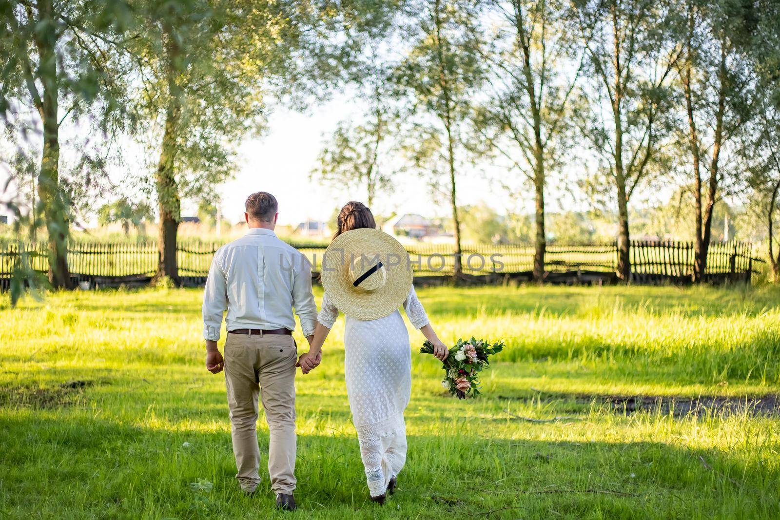 The couple walks across the field. They holds hans. The veil dissipates. In the hands of a bouquet. by Anyatachka