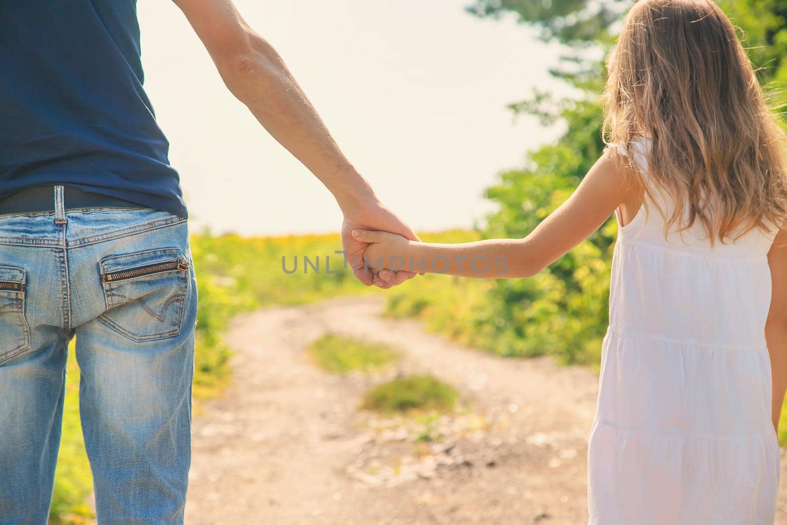 Father and daughter walk holding hands. Selective focus. nature.