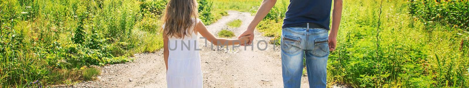 Father and daughter walk holding hands. Selective focus. by yanadjana