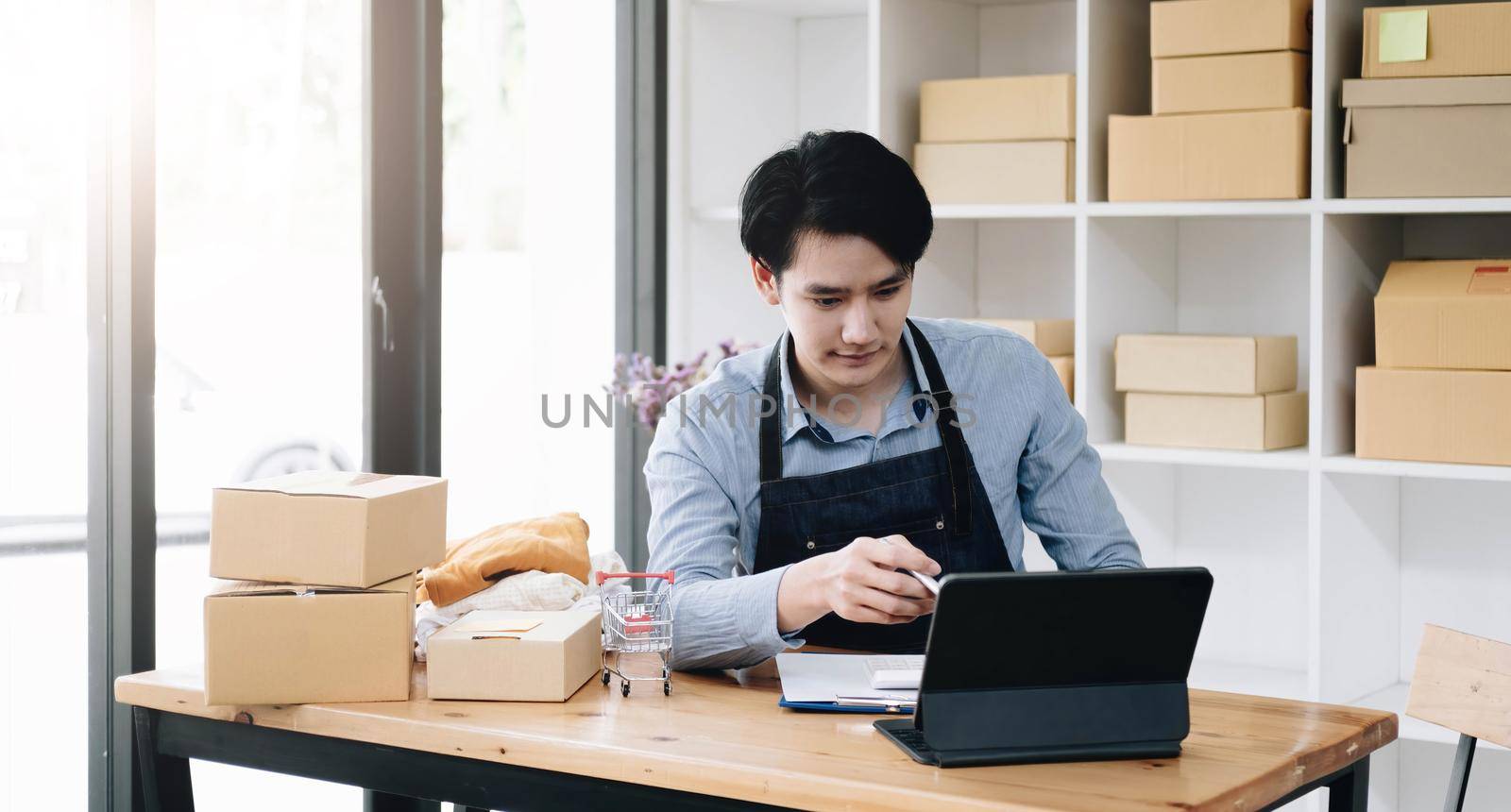 Asian business men use laptop computer checking customer order online shipping boxes at home. Starting Small business entrepreneur SME freelance. Online business, Work at home concept..