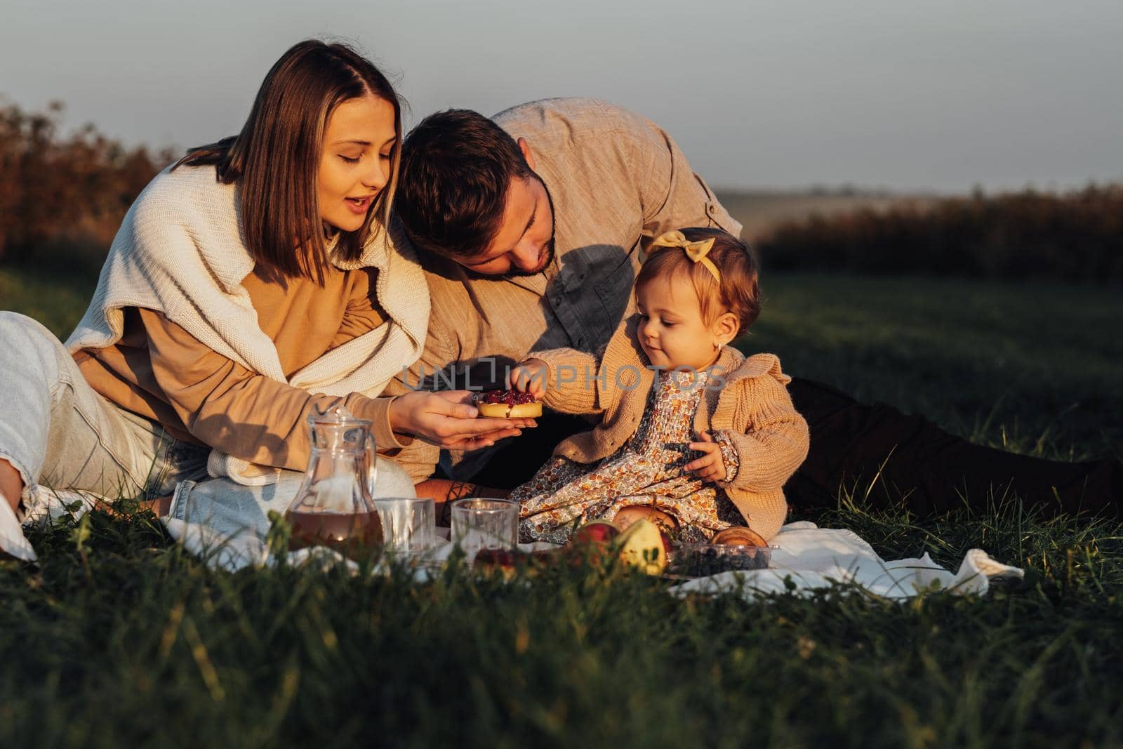 Young Family Enjoying Picnic Outdoors at Sunset, Mom Dad and Baby Daughter on Weekend