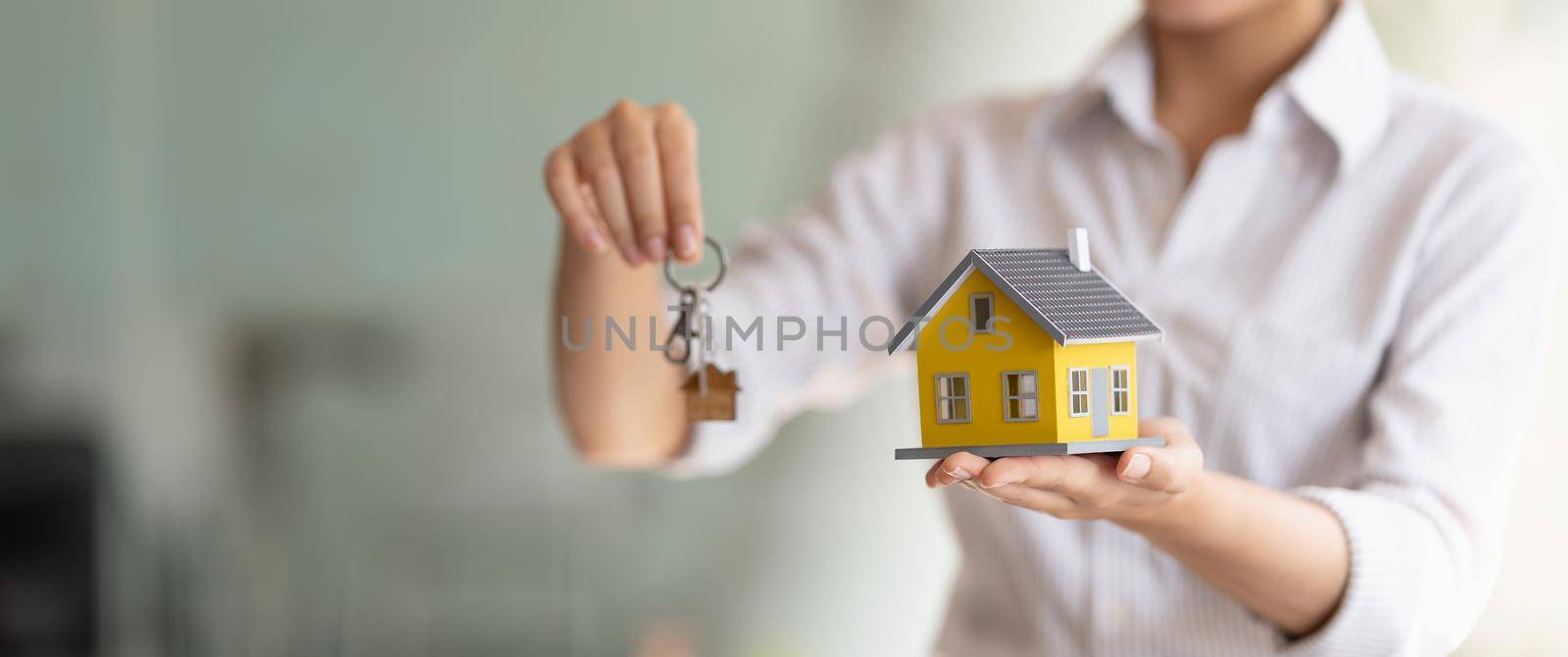 Cropped shot of real estate agent handing keys and home model. by nateemee