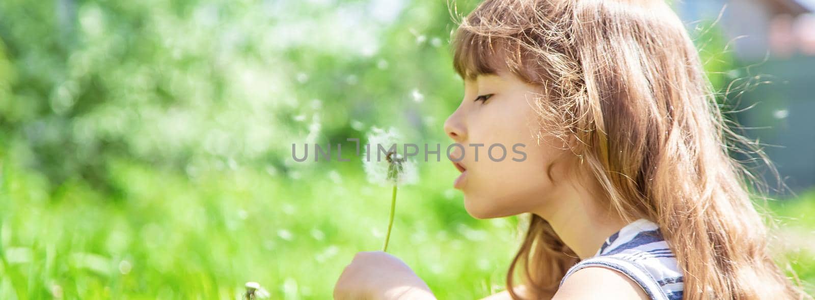 girl blowing dandelions in the air. selective focus.