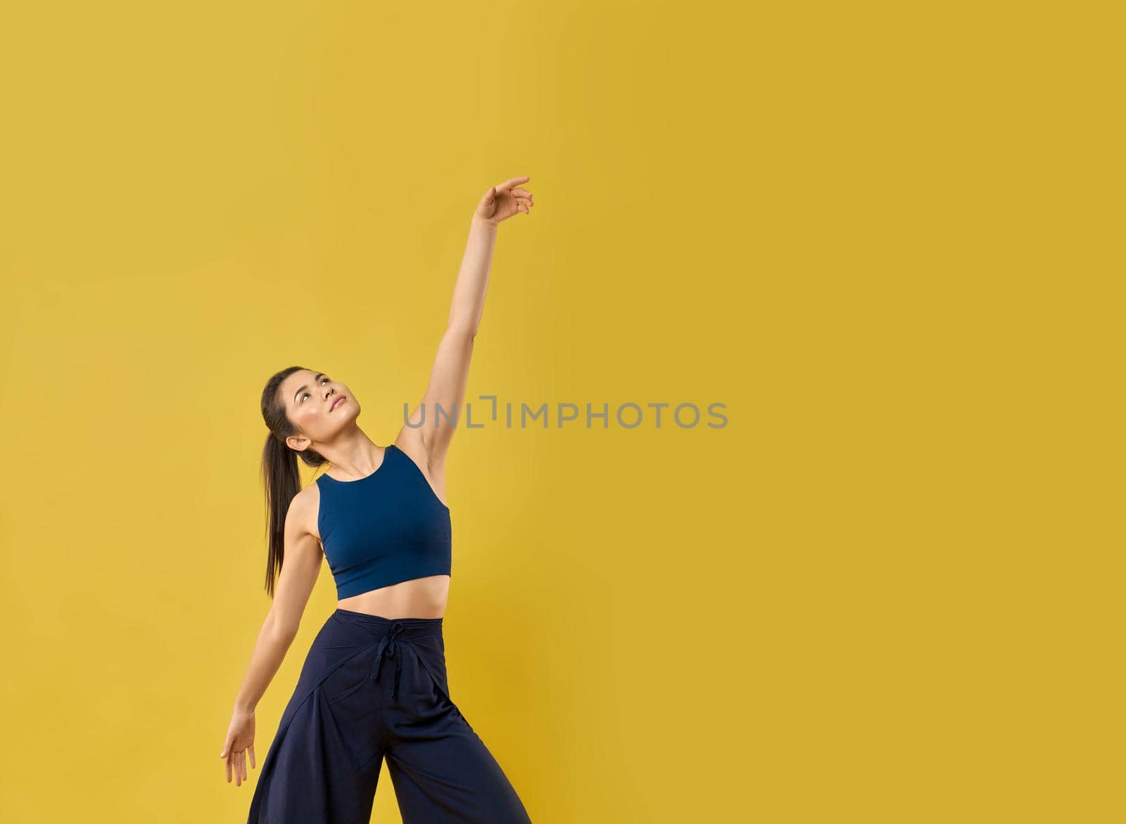 Stylish girl moving arm gracefully while dancing in studio. by SerhiiBobyk