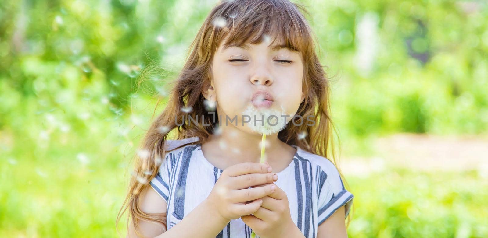 girl blowing dandelions in the air. selective focus.