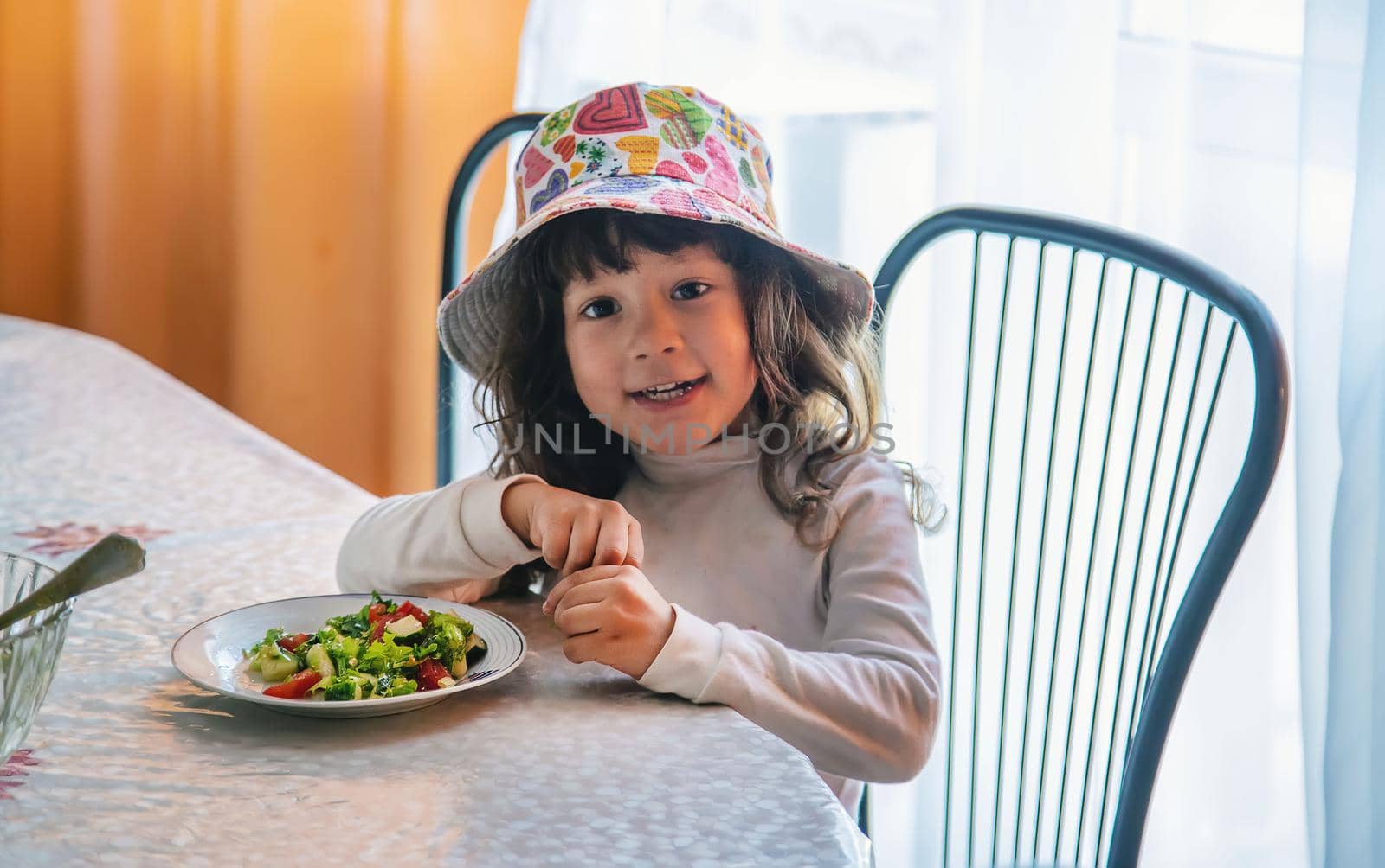 Child girl eats salad at the table. Selective focus. Kid.