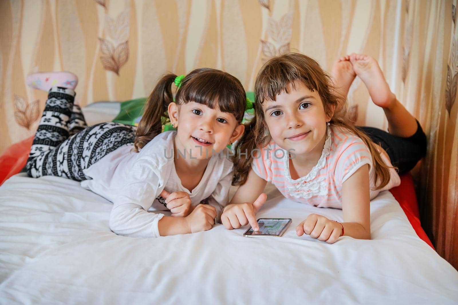 The child is playing the phone on the bed. Selective focus. by yanadjana