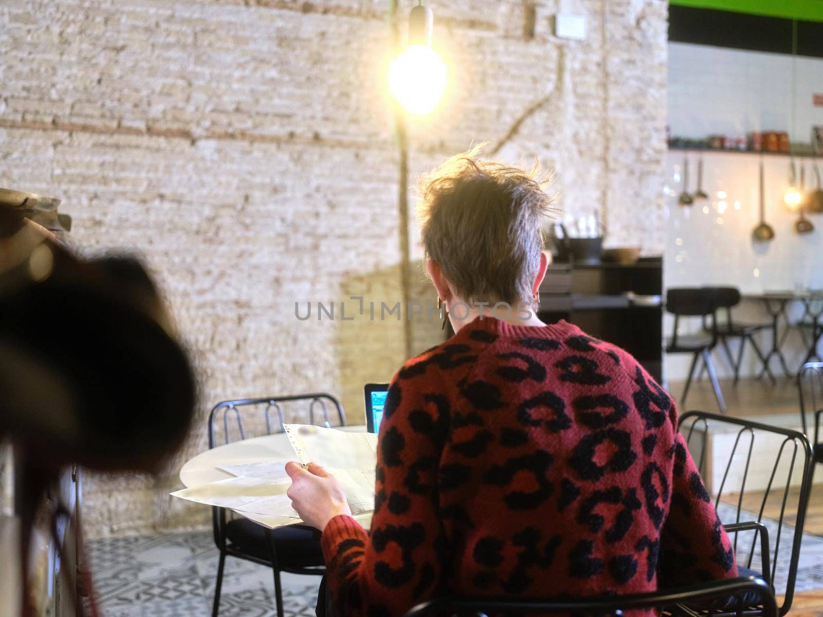 Manager of a restaurant doing the accounting of the business sitting at a table in the restaurant