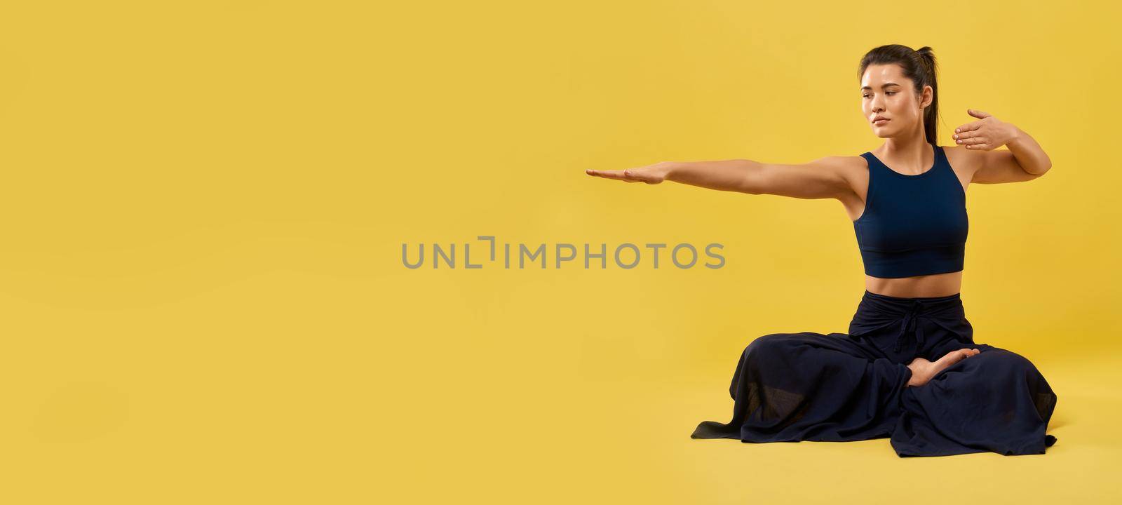 Girl keeping right arm outstretched, while exercising indoor. by SerhiiBobyk