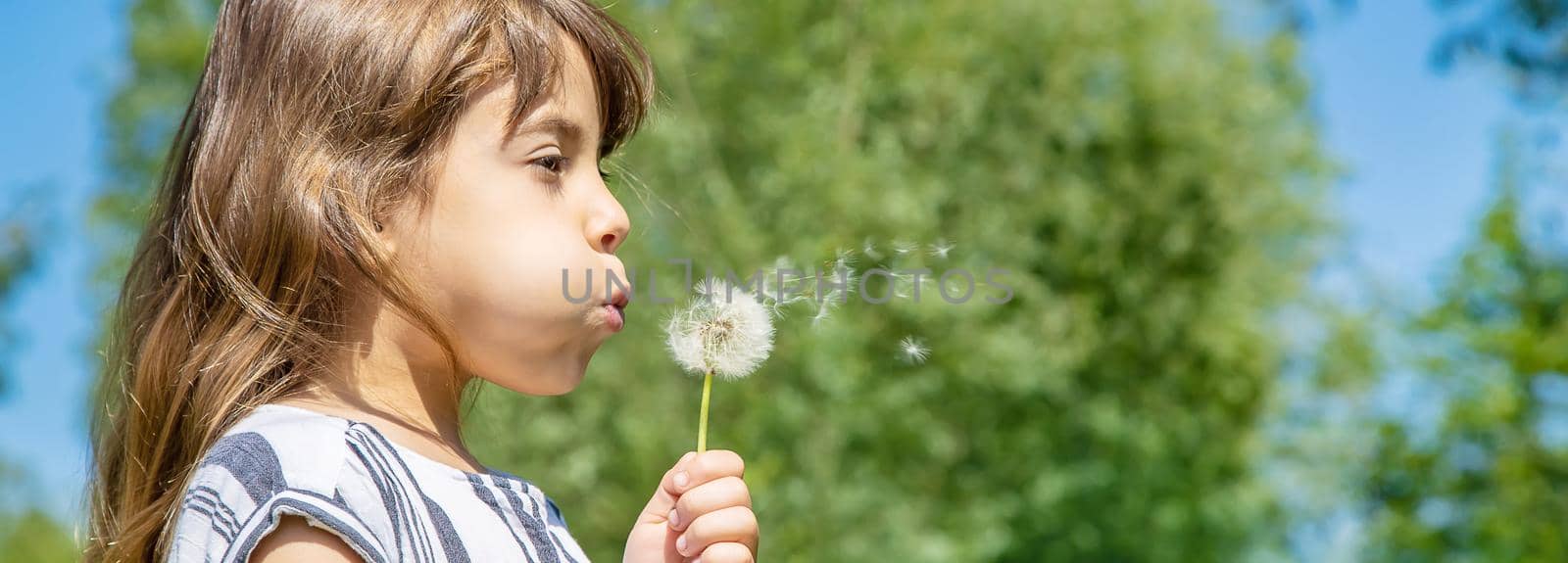 girl blowing dandelions in the air. selective focus. by yanadjana