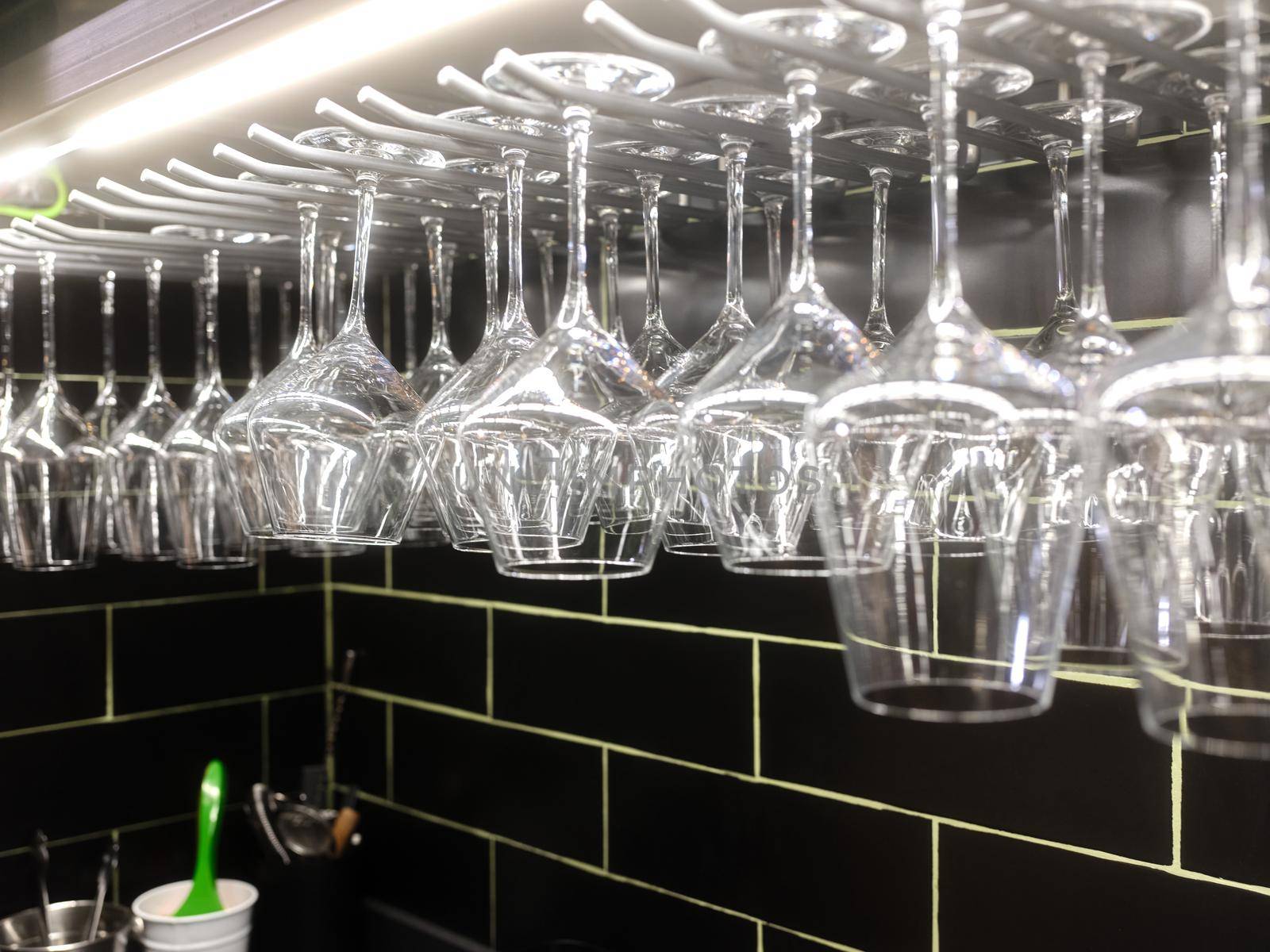 Illuminated clean set of wine glasses hanging from a rack in a restaurant