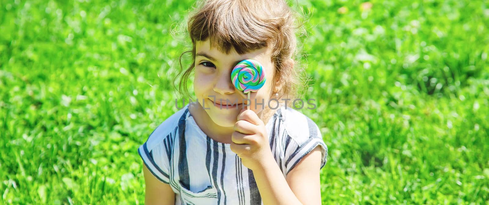 child eats lollipop on nature. Selective focus. by yanadjana