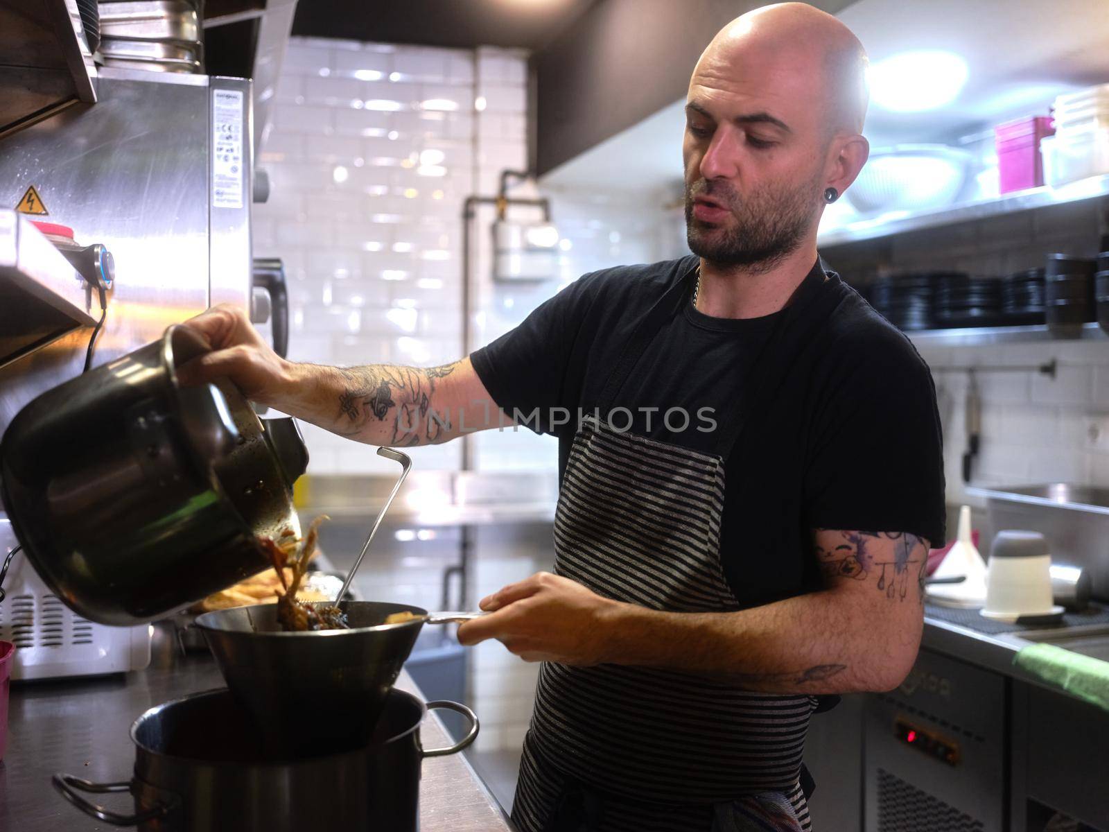 Chef pouring food into a colander in the kitchen of a restaurant by WesternExoticStockers