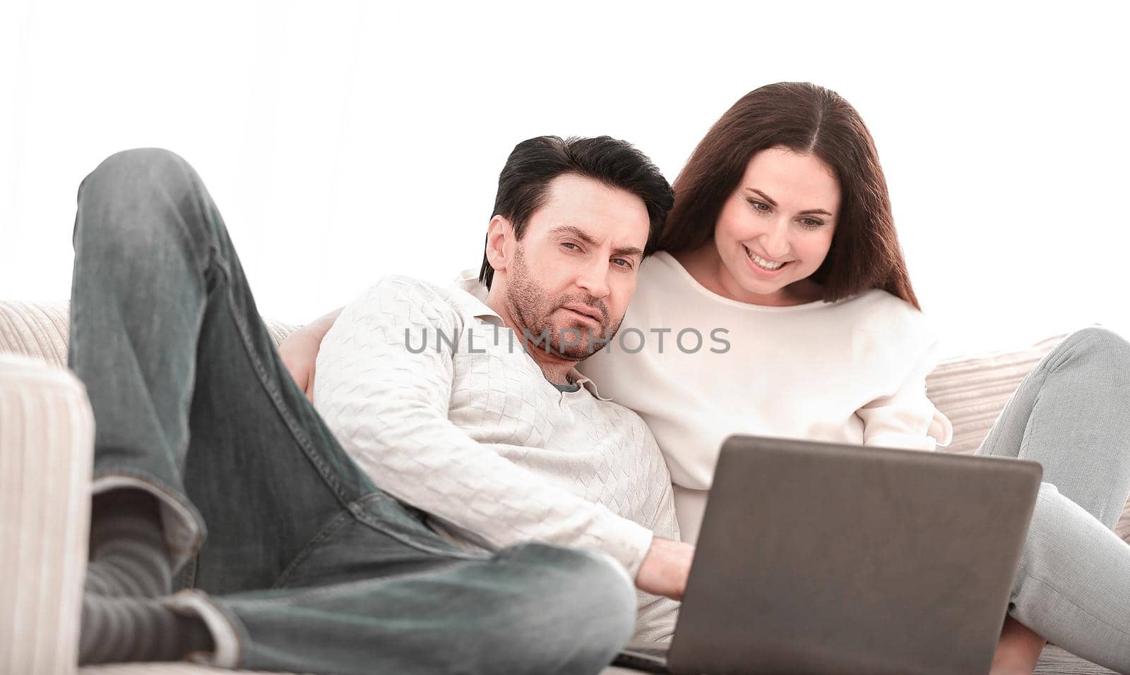 happy couple sitting on the couch in her arms, looking at laptop .people and technology