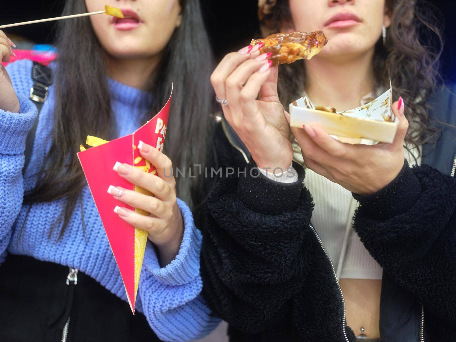 Close up view of two women eating fast food outdoors by WesternExoticStockers
