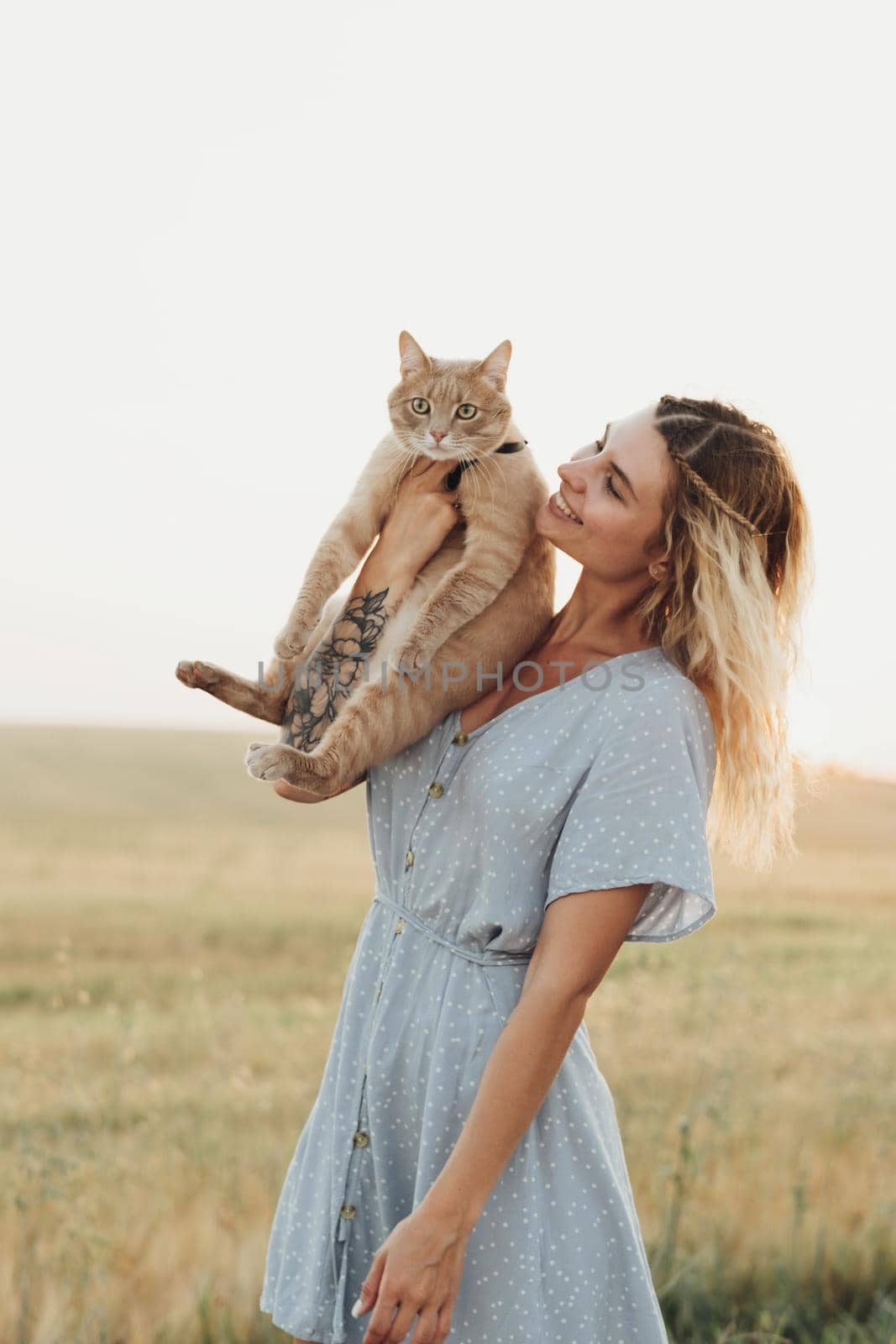 Caucasian Young Woman Dressed in Blue Dress Holding Her Cat Outdoors at Sunset