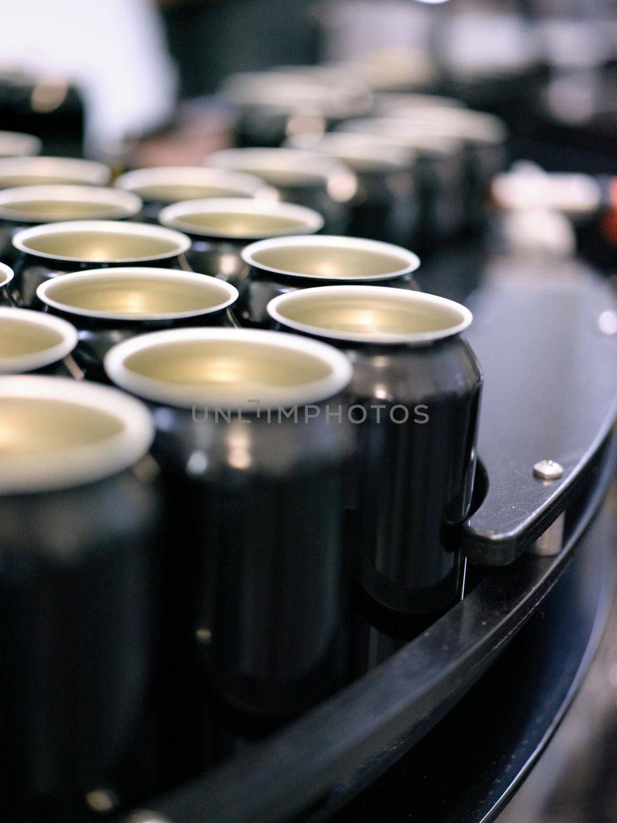 Vertical photo with selective focus on cans of beer placed in a production line in a canning factory