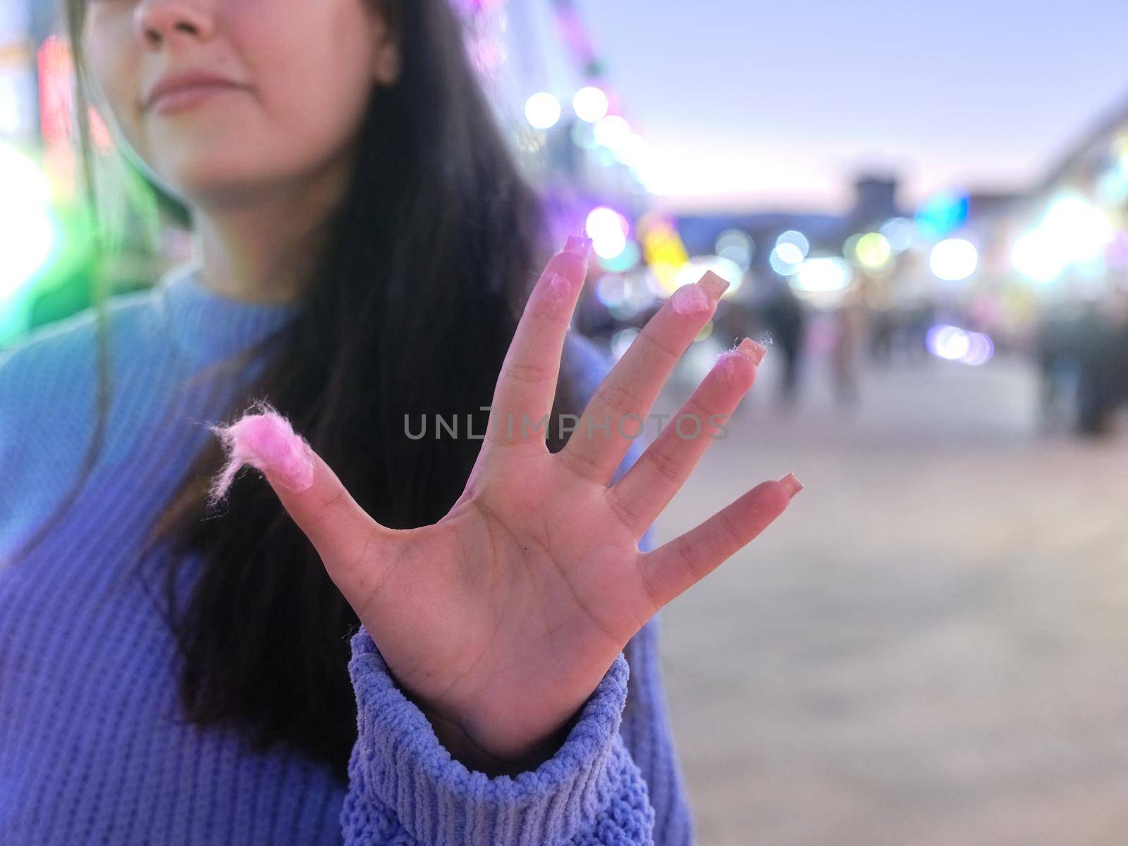 Close up view of a woman showing palm of hand with traces of cotton candy glue to it in a fair