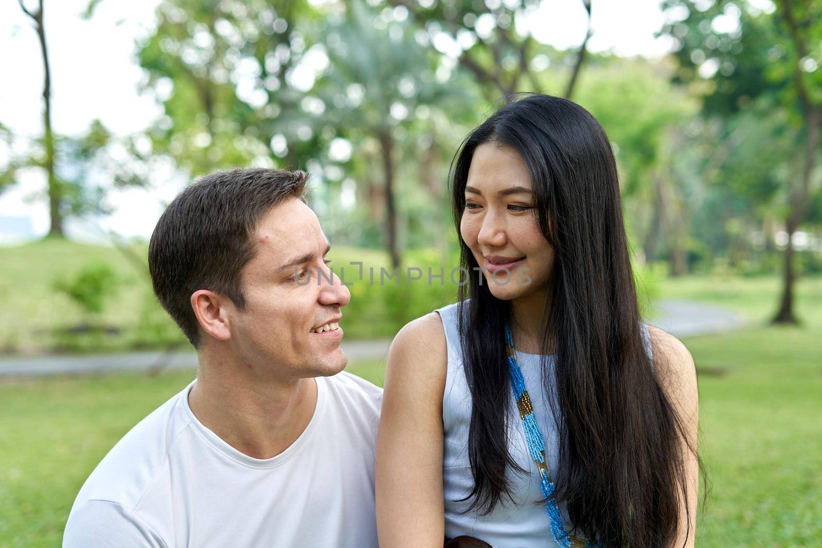 Close up portrait of a multiethnic couple smiling together in a park by WesternExoticStockers
