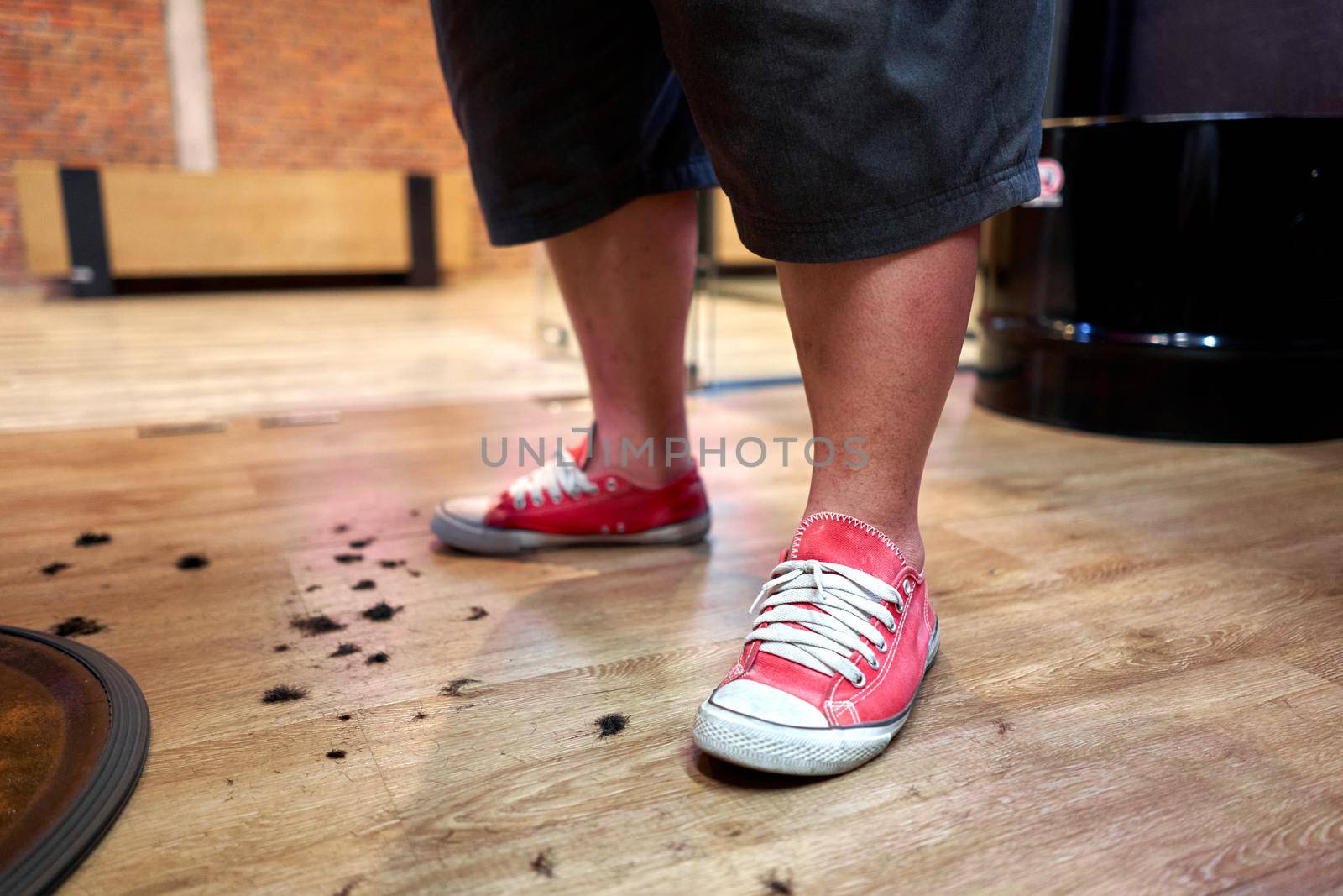 Floor of a barbershop full of hair with the barber standing upright indoors