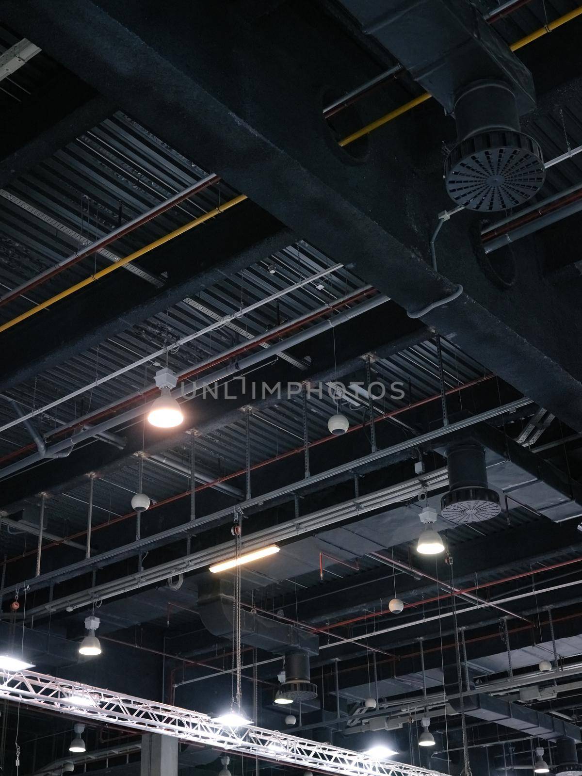 Vertical photo of the ceiling of a trade fair with pipes and safety system tools