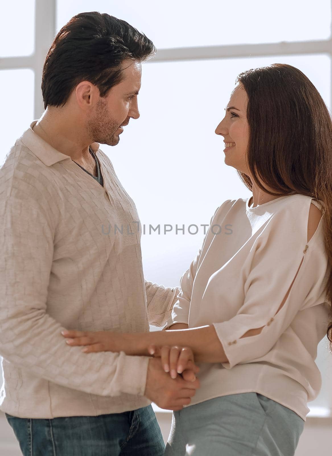 Young happy couple embracing standing near window