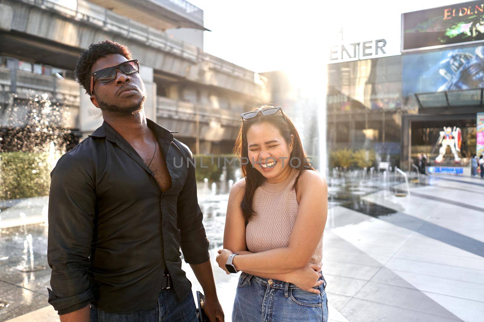 Woman laughing while posing next to an african friend in a mall by WesternExoticStockers