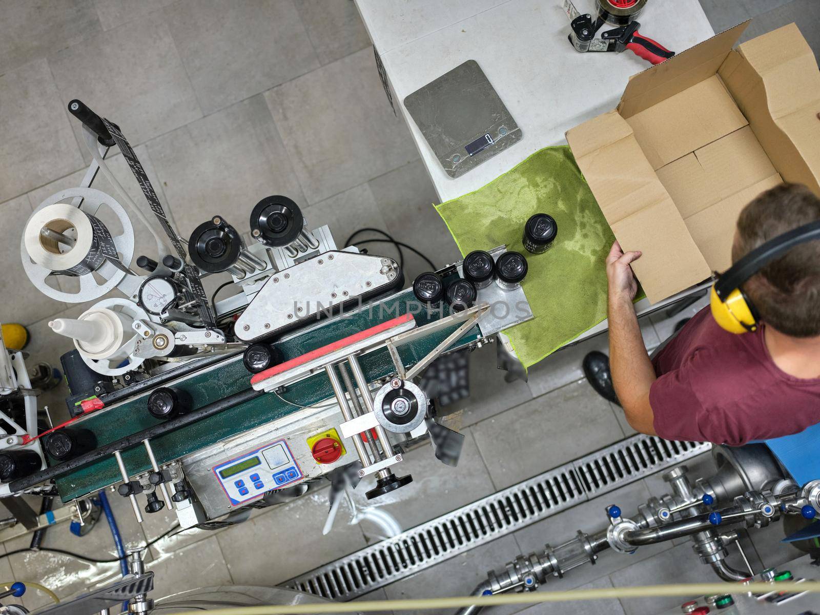 Man standing at the end of a production line while packing cans in a cardboard box in a brewery