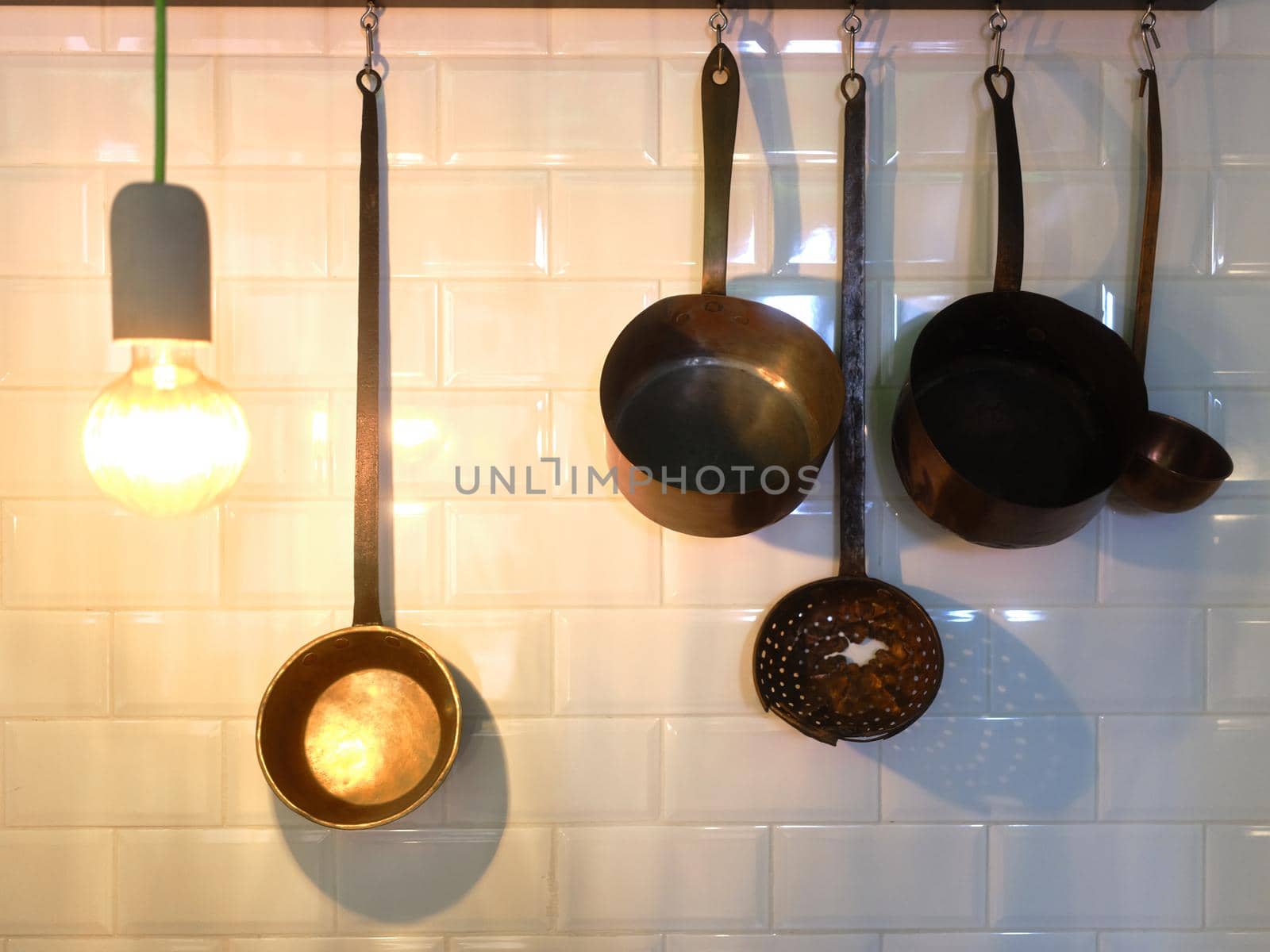 Various kitchen utensils as pots and strainer hanging on the wall of a restaurant.