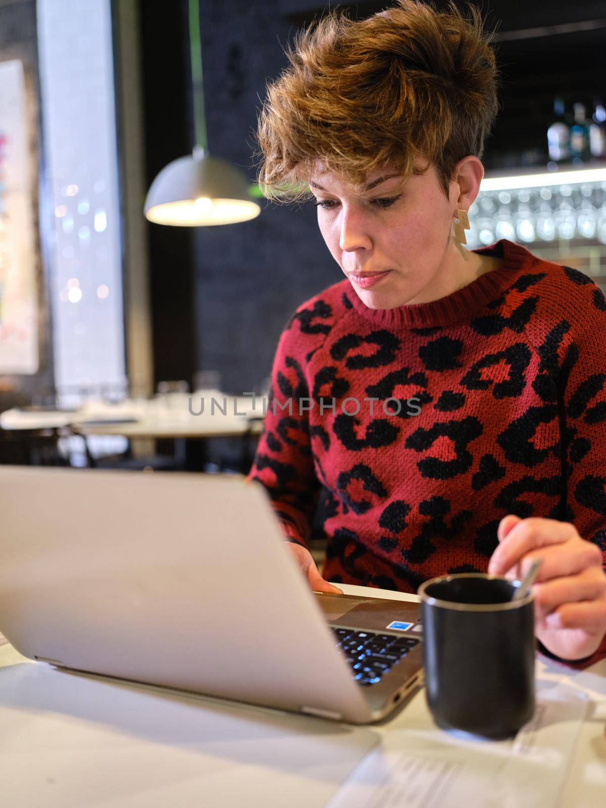 Vertical photo of a female manager of a restaurant working with a laptop inside the establishment