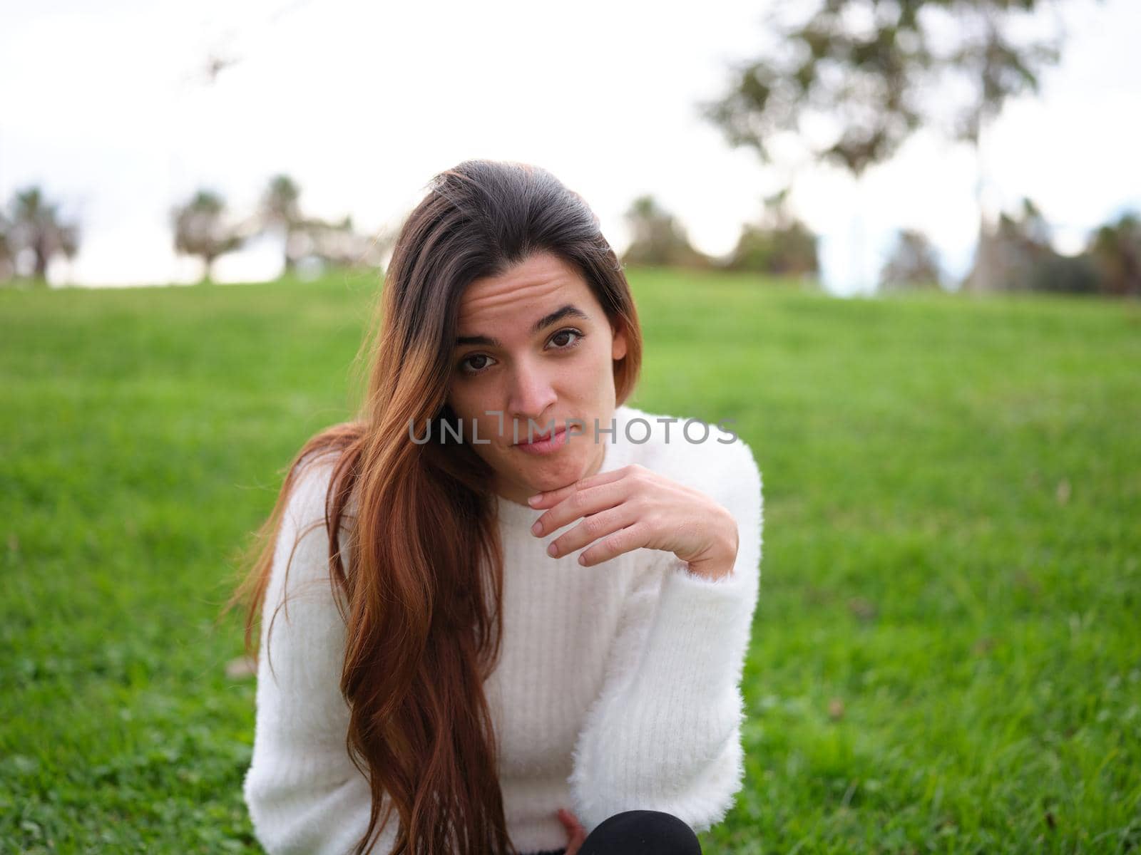 Front view of a young woman in the park looking at the camera feeling missed. Concept of emotions.