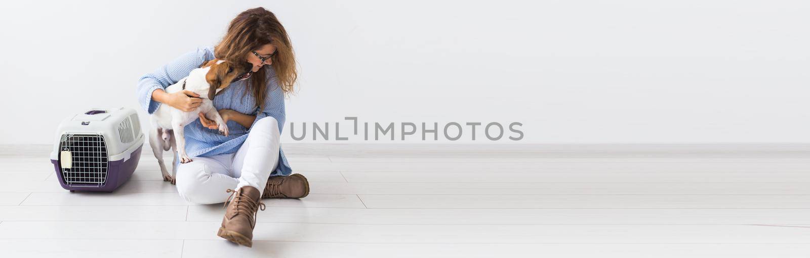 Dog carrying bags and pets owner concept - Attractive cheerful female in blue sweater playing with her favourite pet on white background with copy space banner and place for advertising. woman with her jack russell terrier
