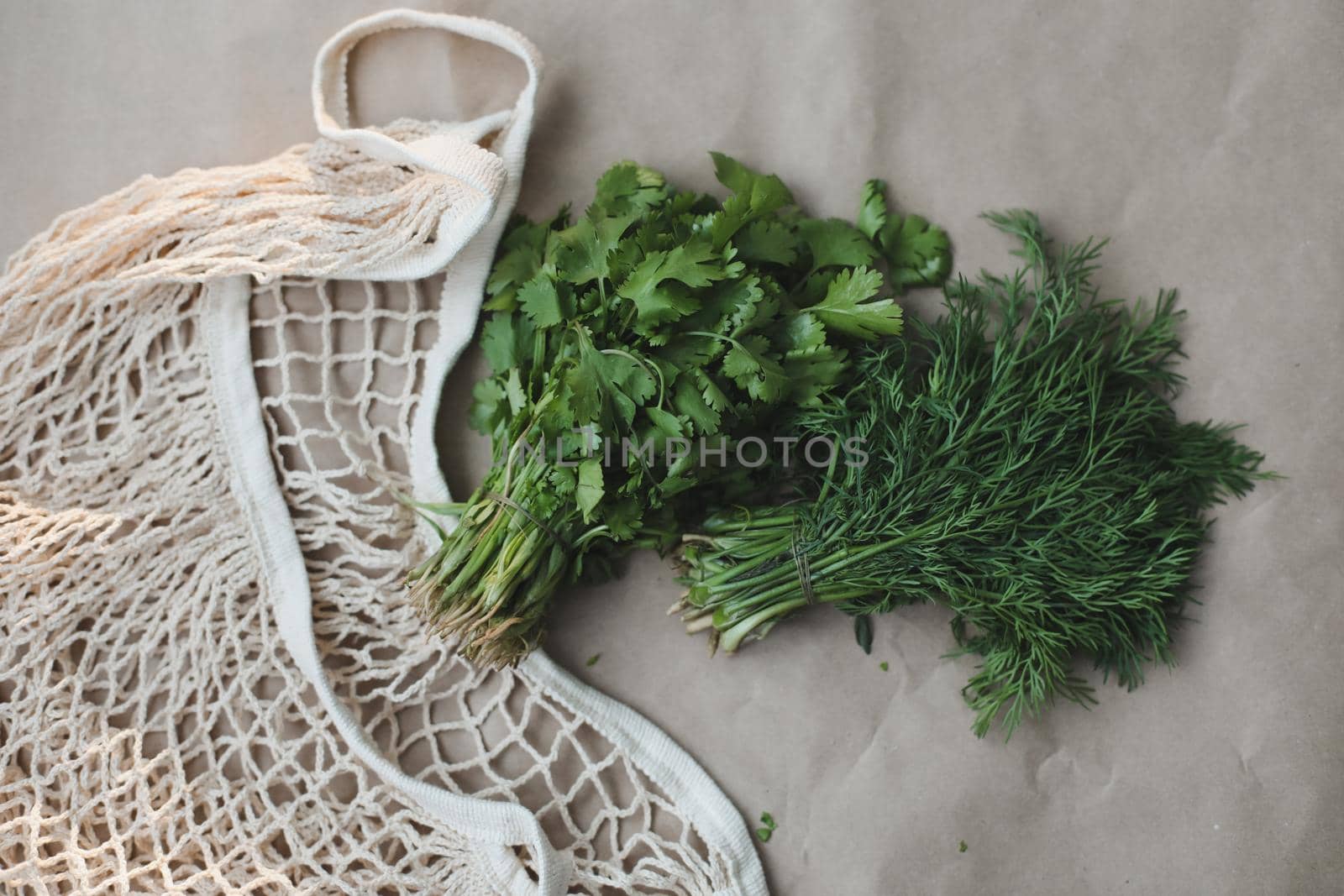 Bunches of fresh greens and organic herbs on beige background. Healthy food. Flat lay, top view, copy space.