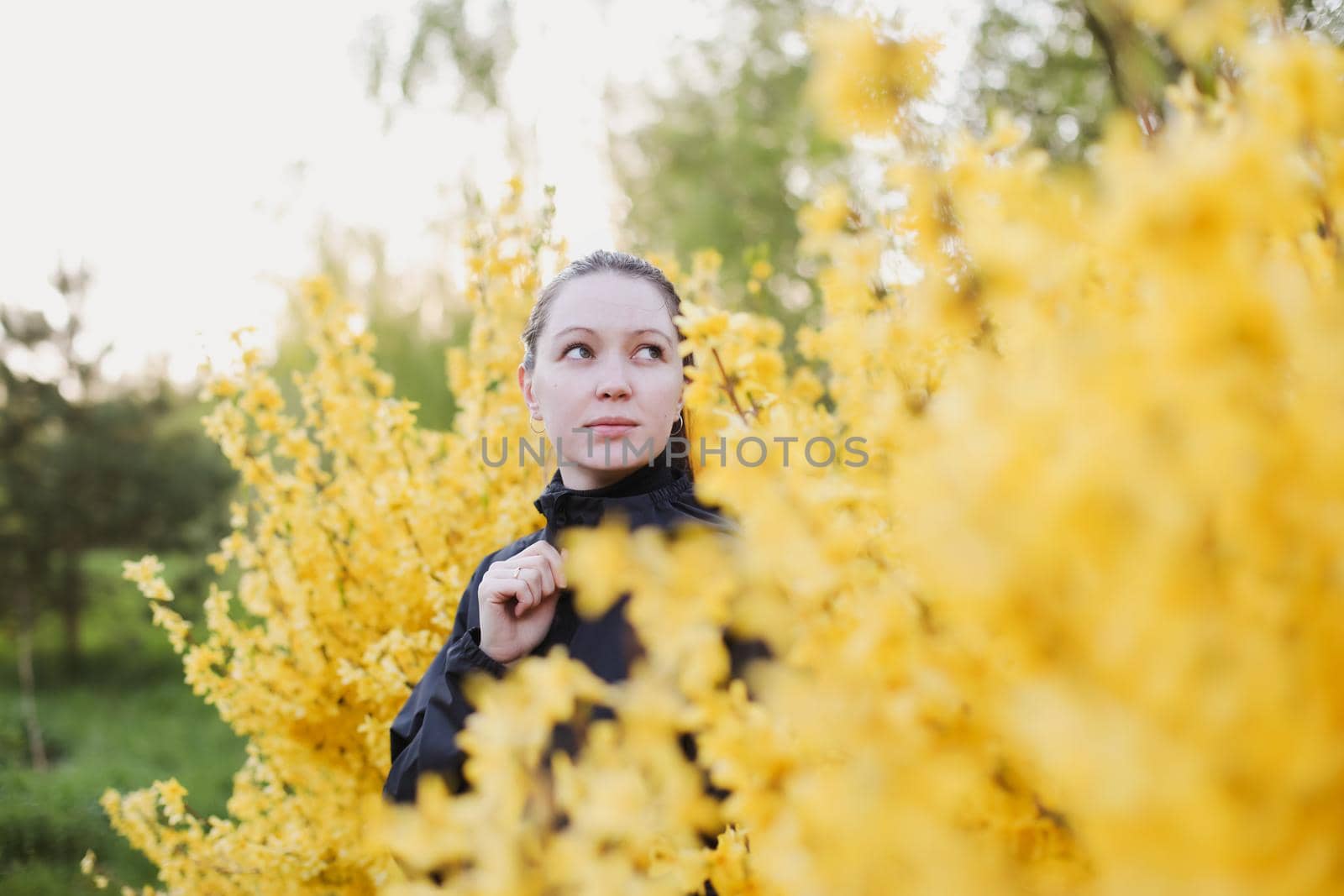 Portrait of young woman posing in blooming spring garden. Girl surrounded with flowers.