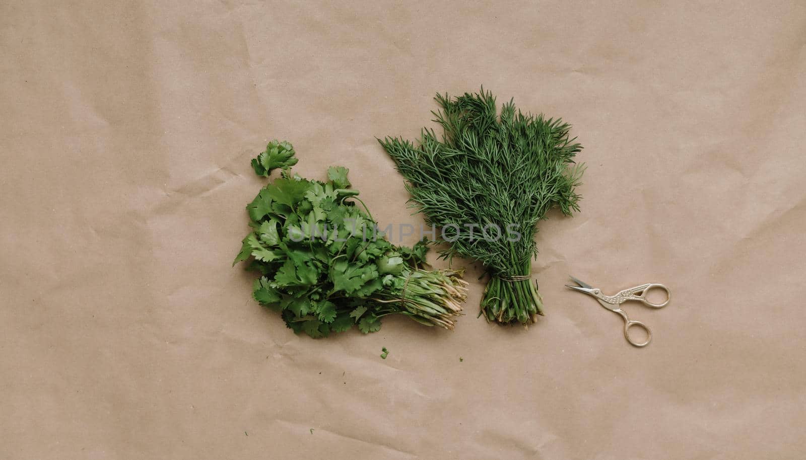 Bunches of fresh greens and organic herbs on beige background. Healthy food. Flat lay, top view, copy space.