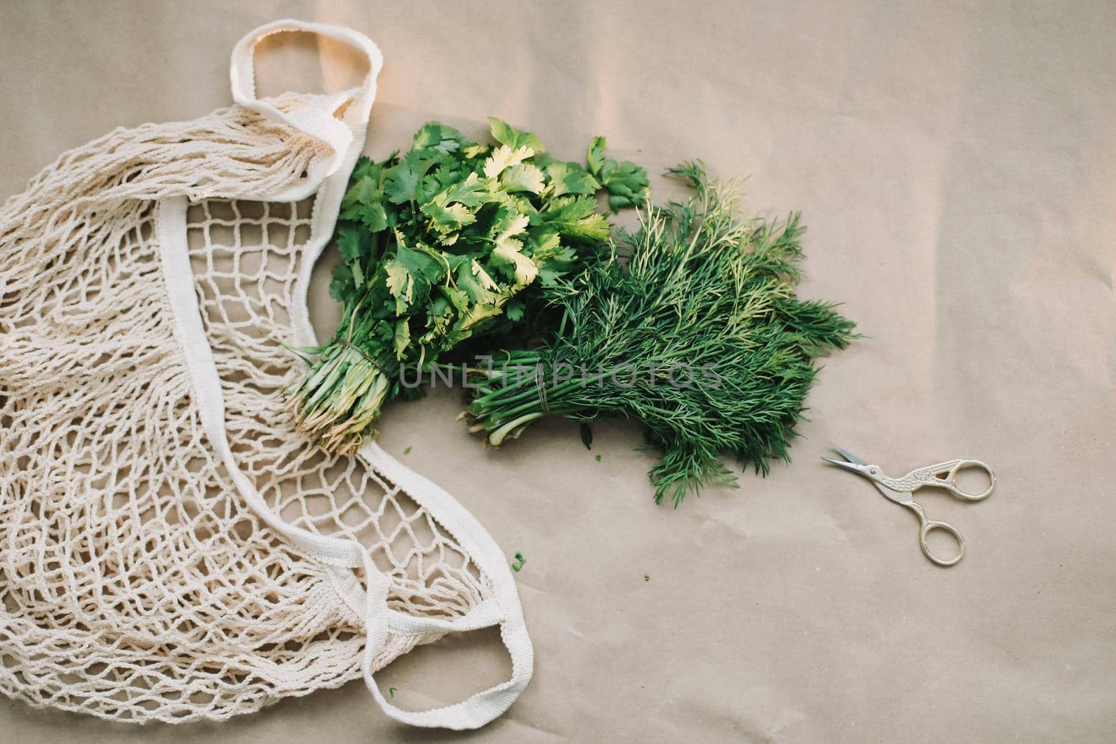 Bunches of fresh greens and organic herbs on beige background. Healthy food. Flat lay, top view, copy space.